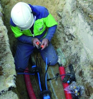 Un technicien installe une ligne électrique dans une tranchée.